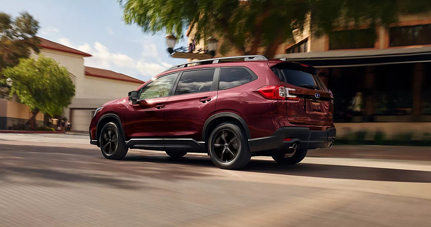 A red Subaru Ascent driving down the road in a neighborhood.