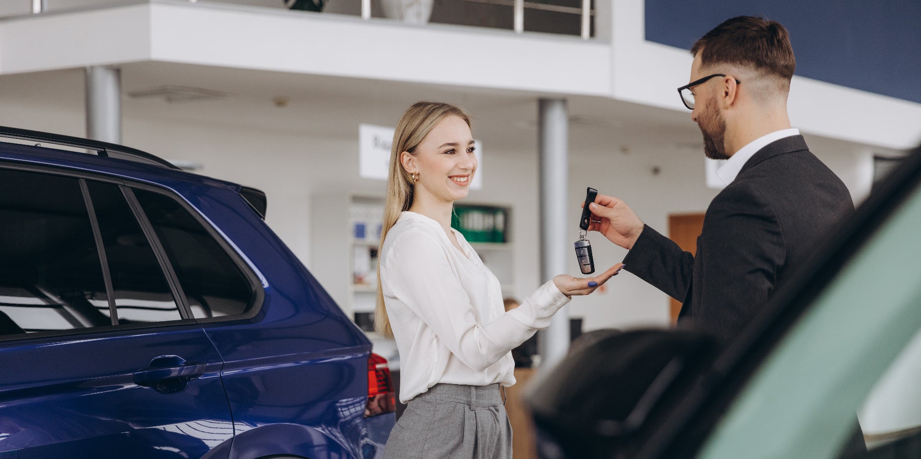 Smiling woman receives the keys to her new Subaru