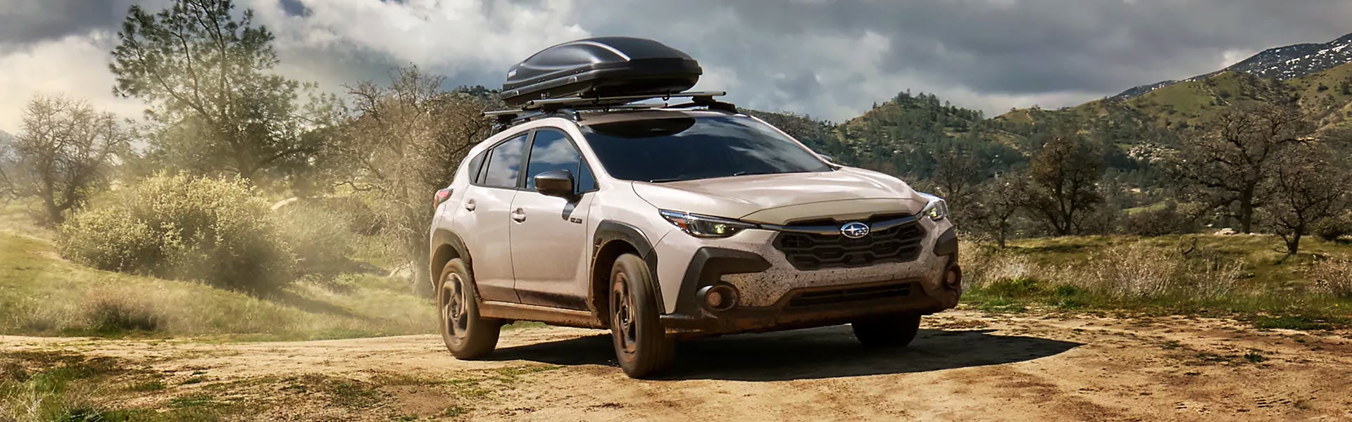 2026 Crosstrek Hybrid parked in a hilly, tree-covered landscape.