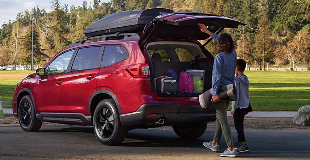 A woman and her child loading up the trunk of a red Subaru Ascent.