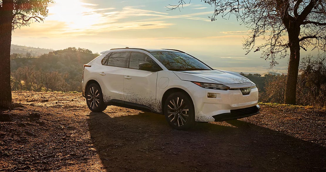 A white Subaru Solterra parked near a ledge off-road.
