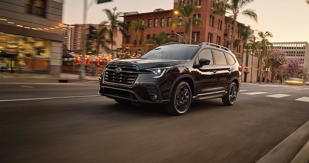 A black Subaru Ascent driving down the road through a town.