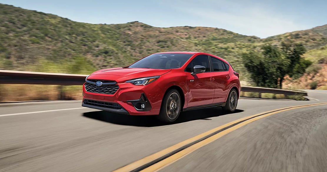 A red Subaru Impreza driving down the road.